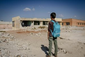 Building Climate-Resilient Schools: Boy with Backpack Looking at Destroyed Building