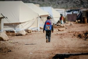 Climate Migration and Education: A Boy Wearing a Backpack Walking on an Unpaved Road